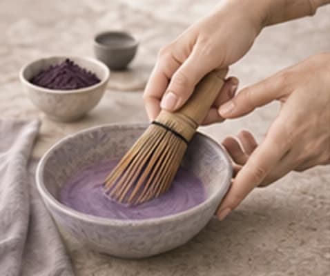 Hands whisking ube powder in a bowl, a gesture of the UBÉRA ritual