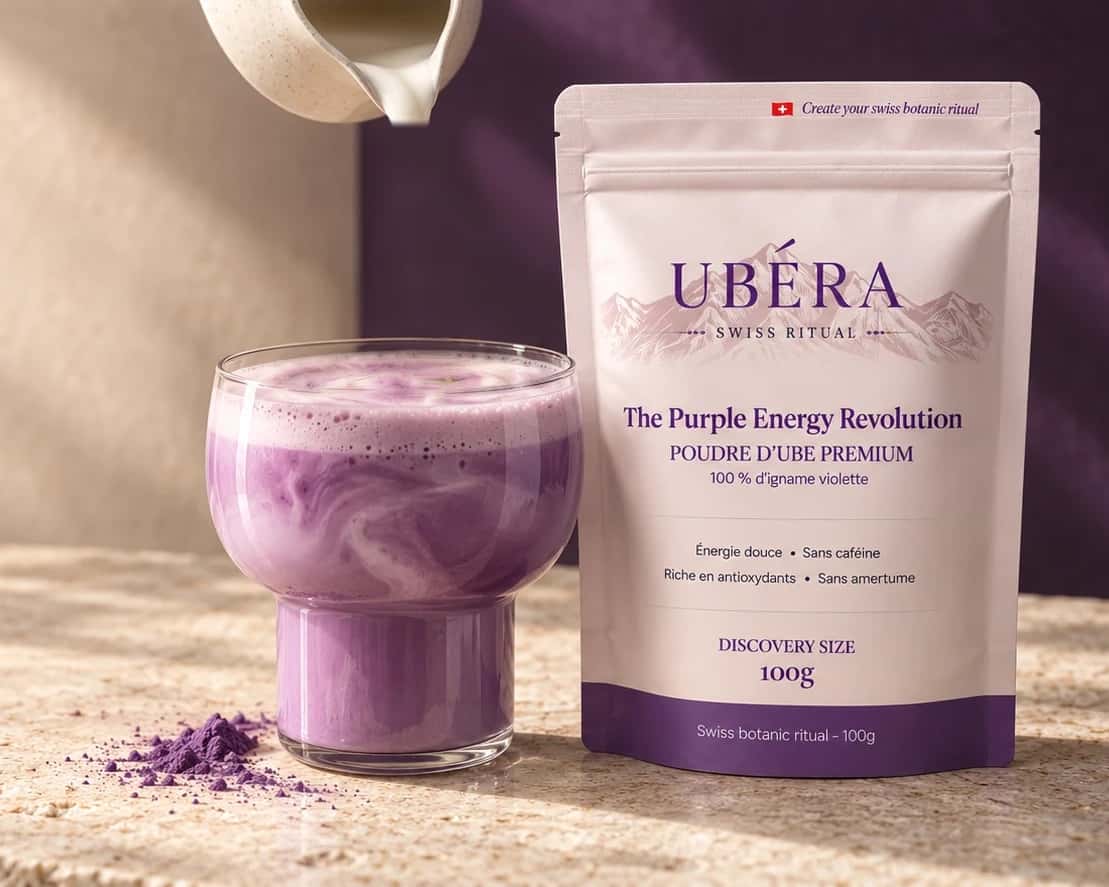Lait versé d'un pichet en céramique dans un latte à l'ube violet, à côté du sachet UBÉRA 100 g, sur un plan de travail en pierre