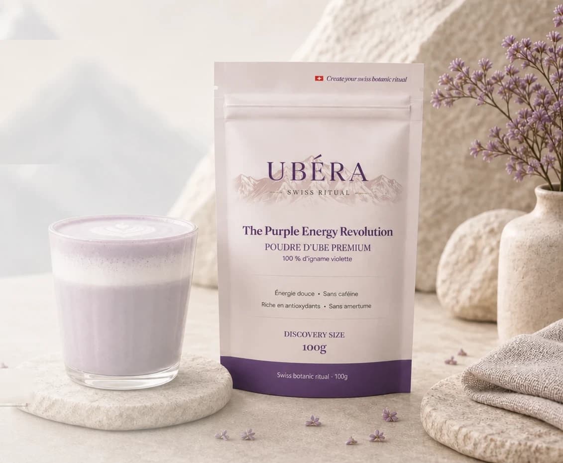 UBÉRA-Ube-Latte auf einem Steinsockel, 100-g-Beutel und Blumen, Schweizer Berge im Hintergrund